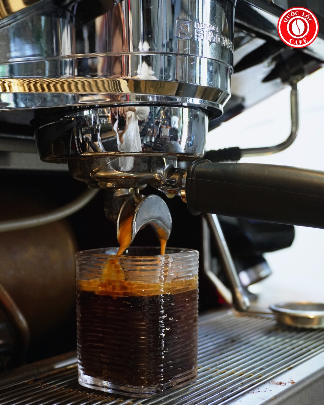 Máy espresso đang chiết xuất cà phê; cảnh báo cà phê trộn gây hư máy do tạp chất và dầu làm nghẹt hệ thống.